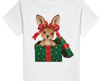 May include: A white short-sleeved t-shirt featuring a graphic of a brown kangaroo joey peeking out of a green gift box with gold stars, a red ribbon, and a red bow tied around the kangaroo's ears. The design is centred on the chest.