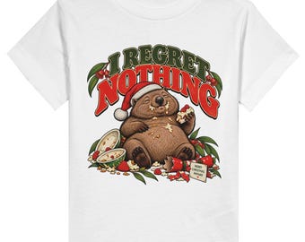 May include: A white t-shirt featuring a graphic of a brown wombat wearing a Santa hat, eating food with crumbs on its face. Above the wombat, the text reads I REGRET NOTHING in red and green. A small card nearby says MERRY CHRISTMAS ANYWAY.