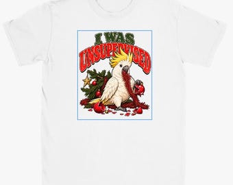 May include: A white short-sleeve t-shirt featuring a graphic of a white cockatoo with a yellow crest. The bird is surrounded by broken red Christmas ornaments and pine branches. The text above the bird reads I WAS UNSUPERVISED.