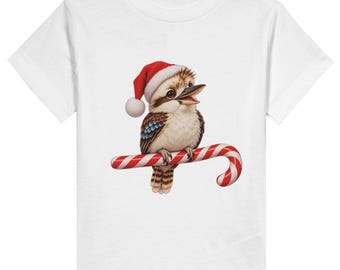 May include: A white short-sleeved t-shirt featuring a graphic of a brown and white kookaburra wearing a red and white Santa hat. The bird is perched on a red and white striped candy cane. The design is centred on the front of the shirt.