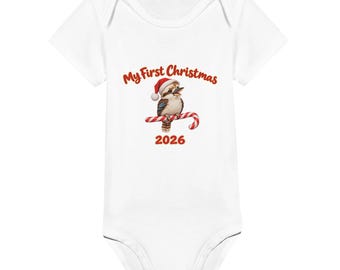 May include: A white short-sleeved baby bodysuit featuring a graphic of a kookaburra wearing a red and white Santa hat, perched on a red and white striped candy cane. The text reads My First Christmas above and 2026 below the graphic.