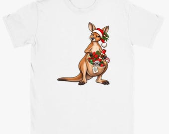 May include: A white t-shirt featuring a graphic of a brown kangaroo wearing a red and white Santa hat. The kangaroo has a pouch filled with Christmas gifts, a candy cane, and a small koala, with a tag reading Keep Calm and Ho Ho Ho.