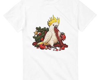 May include: A white short-sleeved t-shirt featuring a graphic of a white cockatoo with a yellow crest. The bird is surrounded by green pine branches, a gold star, and red Christmas baubles, with red tinsel hanging from its beak.