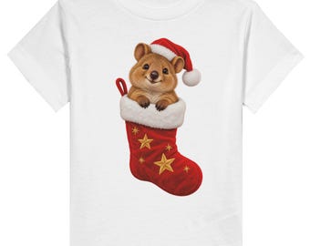 May include: A white short-sleeved t-shirt featuring a graphic of a brown quokka wearing a red Santa hat. The quokka is peeking out of a red Christmas stocking with a white faux fur cuff, decorated with several gold embroidered stars.