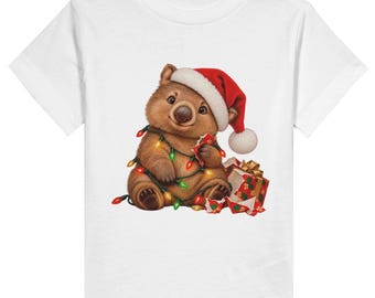 May include: A white t-shirt featuring a graphic of a brown wombat wearing a red and white Santa hat. The wombat is wrapped in a string of colourful Christmas lights and is sitting next to a small gift box with a gold ribbon and red wrapping.