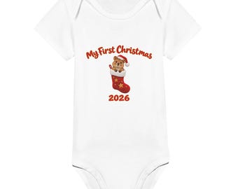 May include: A white short-sleeved baby bodysuit featuring a graphic of a quokka wearing a Santa hat inside a red Christmas stocking. Above the graphic is the red text My First Christmas and below is the red text 2026.