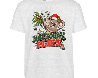 May include: A light grey short-sleeve t-shirt featuring a graphic of a grumpy koala wearing a red Santa hat, swatting at flies with a eucalyptus branch. The text "NOT TODAY, FLIES." is printed in green and red lettering below the koala.