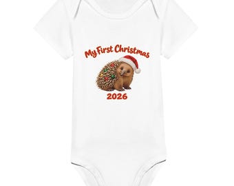 May include: A white short-sleeved baby bodysuit featuring a graphic of an echidna wearing a red and white Santa hat with colourful ornaments on its spines. The text above reads My First Christmas and the year 2026 is printed below in red.