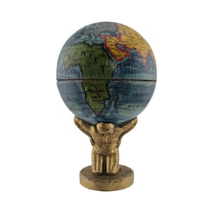 May include: A vintage-style globe, featuring a detailed map of the world, is held aloft by a gold-colored Atlas figure. The globe is split in half, revealing the interior. The base and Atlas figure have a metallic finish.