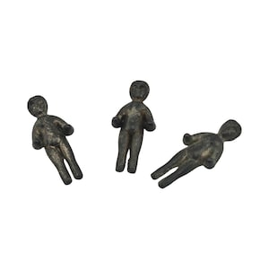 May include: Three small, dark metal figurines in the shape of human figures. The figures are in different poses, with arms extended or at their sides. The figurines have a weathered appearance.