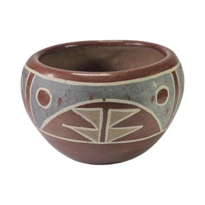 以下が含まれることがあります： テラコッタ色のベースと縁を持つ丸みを帯びた陶器のボウル。外側は、テラコッタ色の円と、中央の三角形のモチーフを含む白で縁取られた幾何学的な形が描かれた、幅の広いまだら模様のグレーの帯で装飾されています。