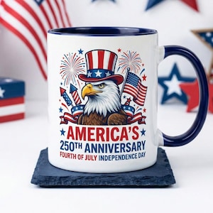 May include: A white ceramic mug with a blue handle and rim, featuring a patriotic design for America's 250th Anniversary. The design includes an eagle wearing a top hat, fireworks, and American flags. The text reads "America's 250th Anniversary Fourth of July Independence Day."