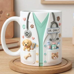 Può includere: Tazza in ceramica bianca con un design da camice veterinario, tra cui uno stetoscopio, impronte di zampe e tasche con un cucciolo, un osso e un gatto. La tazza ha il testo "DR. EMILY".