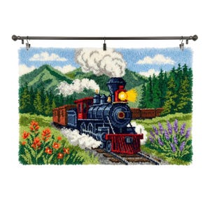 Puede incluir: Un tapiz rectangular de ganchillo con una locomotora de vapor azul oscuro, un apartavacas rojo y un faro amarillo brillante, que viaja a través de un paisaje montañoso verde con flores silvestres de color naranja y morado en primer plano.