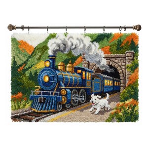 Puede incluir: Un tren azul con detalles dorados emerge de un túnel en un paisaje colorido. Un perro blanco corre junto al tren por un camino. La obra de arte está montada en una barra de cortina marrón oscuro con terminales decorativos.