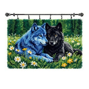 May include: A rectangular latch hook wall hanging featuring two wolves, one blue and one black, resting in a field of green grass with white and yellow daisies. The textile art is suspended from a black metal rod with six silver clips.