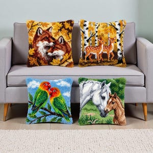 May include: Four decorative throw pillows with nature-themed designs. One pillow features two foxes in autumn leaves, another shows two deer in a birch forest, a third displays two lovebirds, and the last depicts a horse and foal.
