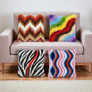 May include: Four decorative throw pillows with textured, shaggy surfaces. Designs include a brown and white chevron pattern, a rainbow wave, a black and white zebra stripe with a red accent, and a blue, red, and white wavy pattern.
