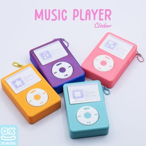 Può includere: Quattro portachiavi per lettore musicale colorati in arancione, viola, rosa e verde acqua. Ogni lettore ha uno schermo bianco con una grafica e un pannello di controllo circolare bianco. Il testo "MUSIC PLAYER" e "Clicker" sono in alto.
