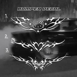 May include: Three white bumper decal designs labeled 1, 2, and 3. Design 1 features a Hello Kitty character with tribal-style wings and stars. Design 2 shows a central heart with tribal wings. Design 3 displays a butterfly with tribal wings.