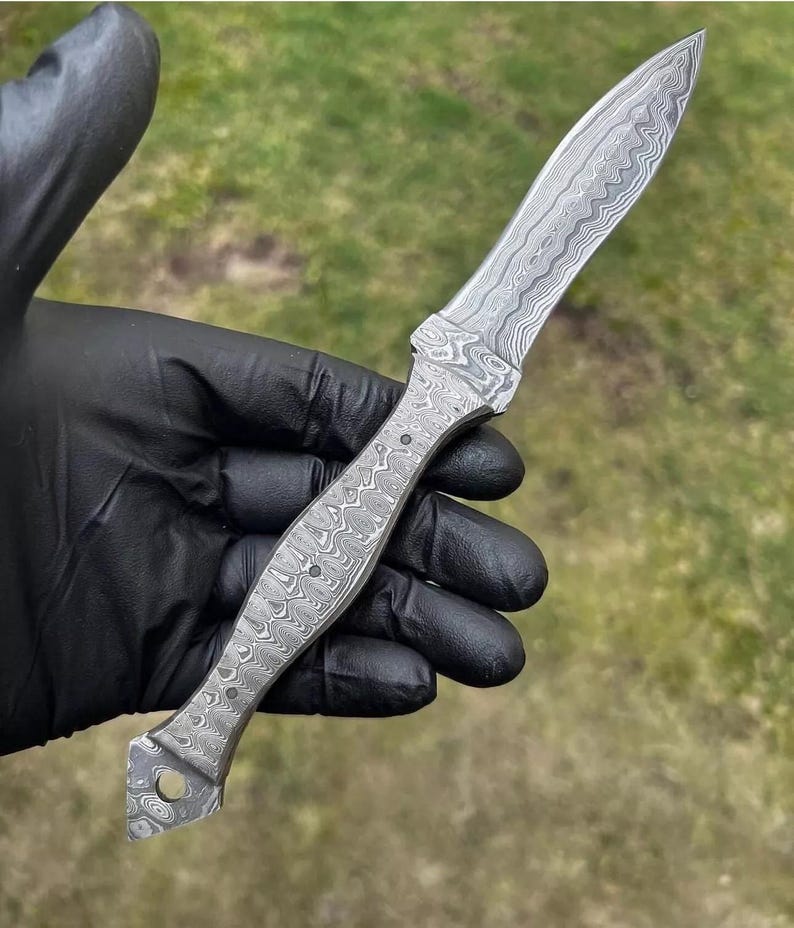 May include: A Damascus steel knife with a patterned blade and handle. The knife has a pointed tip and a handle with a series of small, round indentations. The blade and handle have a swirling, textured appearance.