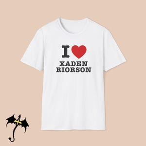 May include: White t-shirt with the text "I ♥ XADEN RIORSON" in black and red. The heart symbol is red. The shirt has a crew neck.