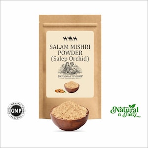 May include: A brown paper bag with a label that reads "SALAM MISHRI POWDER (Salep Orchid)". A wooden bowl filled with beige powder sits in front of the bag. The words "Natural n Tasty" are in green script.