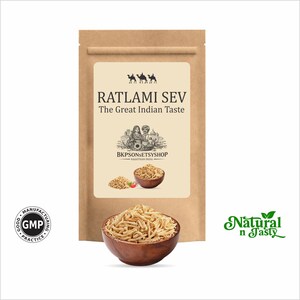 Puede incluir: Una bolsa de papel marrón con la etiqueta "RATLAMI SEV The Great Indian Taste". Se ve un cuenco de madera lleno del producto, así como un cuenco más pequeño y un montón del producto. Las palabras "Natural n Tasty" están en verde.