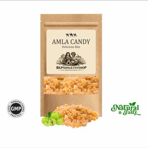 Könnte beinhalten: Ein brauner Papiertüte mit Amla-Bonbons mit einem transparenten Fenster, das die Süßigkeiten zeigt. Auf dem Etikett steht "AMLA CANDY Delicious Bite" mit dem Text "BKPSONSETSYSHOP RAJASTHAN INDIA". Ein Haufen Süßigkeiten und grüne Früchte befinden sich vor der Tüte.