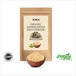 May include: A kraft paper bag with a label that reads "Organic Ashwagandha Root Powder." A wooden bowl filled with light brown powder sits in front of the bag. The words "Natural n Tasty" are in green script on the right.