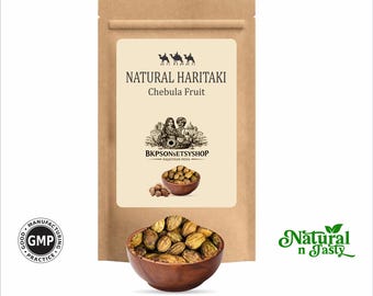 Puede incluir: Una bolsa de papel marrón con la etiqueta "Natural Haritaki Chebula Fruit". Un cuenco de madera lleno de fruta verde-marrón está delante de la bolsa. El texto "Natural n Tasty" está a la derecha.