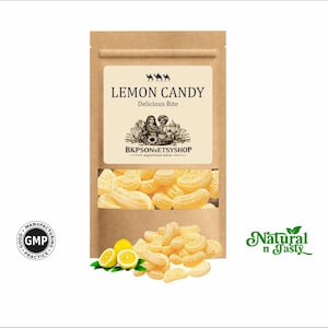 Può includere: Un sacchetto di carta marrone con caramelle al limone. L'etichetta recita "LEMON CANDY Delicious Bite" e "BKPSONSETSYSHOP RAJASTHAN INDIA". Le caramelle gialle hanno la forma di fette di limone. La borsa ha un logo "Natural n Tasty".