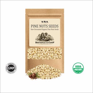 Könnte beinhalten: Ein brauner Papiersack mit rohen, ungerösteten Bio-Pinienkernen. Der Beutel hat ein klares Fenster, das die Samen zeigt. Das Etikett lautet "PINE NUTS SEEDS" und "BKPSONSETSYSHOP". Ein USDA Organic-Siegel ist sichtbar.