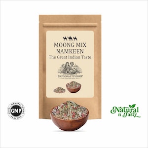 May include: A brown paper bag with a label that reads "MOONG MIX NAMKEEN The Great Indian Taste." A wooden bowl filled with a mix of spices and herbs is in front of the bag. The words "Natural n Tasty" are in green script.