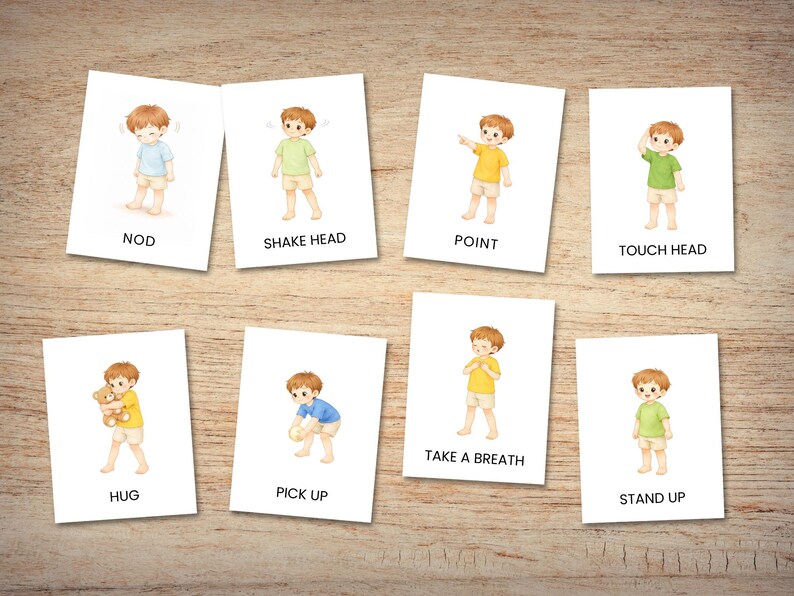 May include: Eight flashcards with illustrations of a child demonstrating various actions. The cards include actions like "NOD," "SHAKE HEAD," "POINT," and "TOUCH HEAD." The child is wearing different colored shirts. The cards are on a wooden surface.