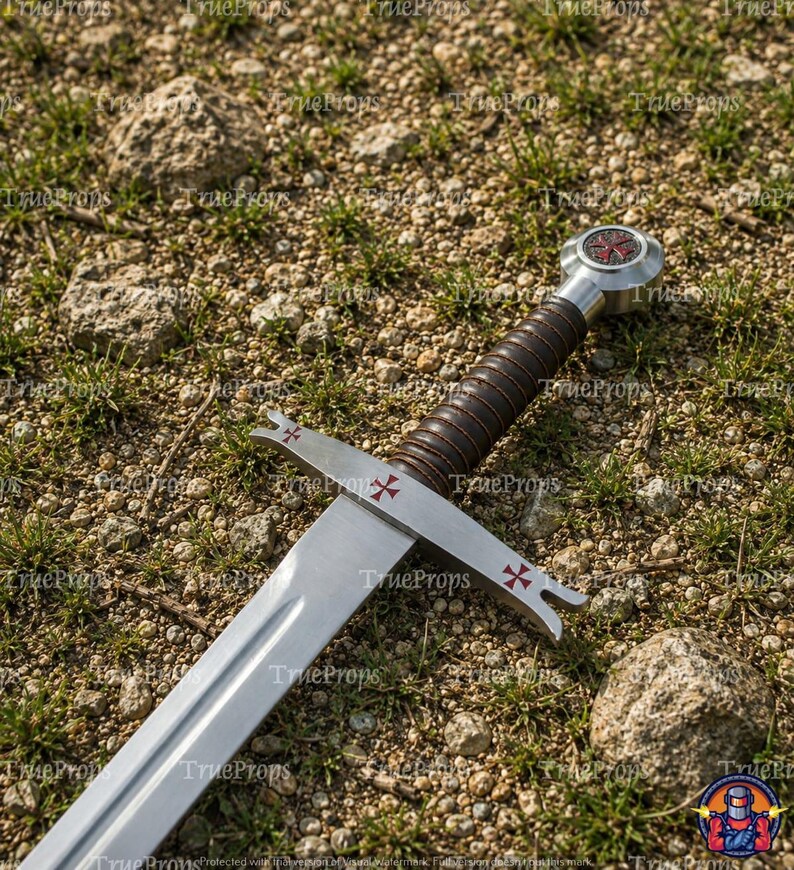 May include: A silver-toned metal sword featuring a dark brown ridged grip and a circular pommel. The crossguard and pommel are decorated with small red cross symbols. The blade is straight with a central fuller running down the length of the metal.