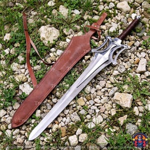 Puede incluir: Una espada de acero de doble filo con una compleja guarda de metal calado y un mango envuelto en color marr&oacute;n oscuro. La espada viene acompa&ntilde;ada de una funda de cuero marr&oacute;n a juego con una correa ajustable integrada para llevarla.
