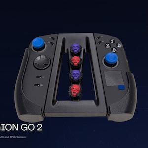 Può includere: Un accessorio controller nero per Legion Go 2 dotato di due joystick blu, un pad direzionale e quattro pulsanti azione etichettati A, B, X, Y. Il ponte centrale ospita quattro piccole teste di demone scolpite in colori viola e rosso alternati.