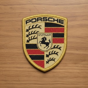 May include: Embroidered patch featuring the Porsche logo. The patch has a gold border and a shield design with the word "PORSCHE" at the top. The shield includes black, red, and tan sections, with a black horse in the center and the word "STUTTGART".