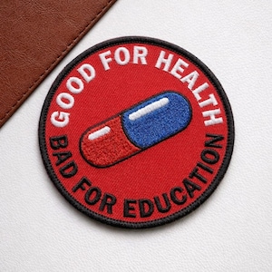 May include: Embroidered patch with a red background and a blue and red capsule design. The patch has the text "GOOD FOR HEALTH" and "BAD FOR EDUCATION" in white, with a black border. The patch is round.