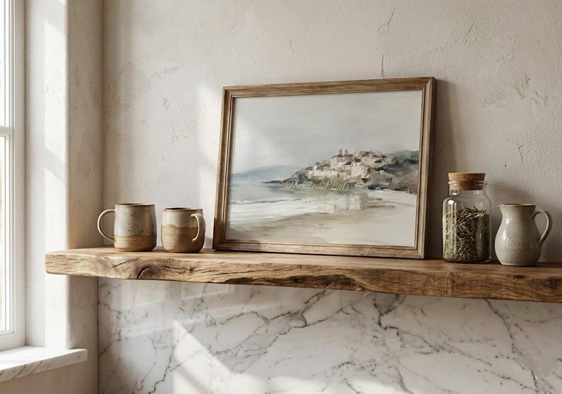 Puede incluir: Una estanter&iacute;a de madera exhibe una pintura enmarcada de un paisaje costero, dos tazas de cer&aacute;mica, un tarro de cristal con tapa de corcho y una jarrita. Los objetos son de tonos neutros.