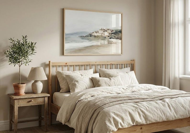 Puede incluir: Un dormitorio con una cama de madera con ropa de cama y almohadas beige. Una pintura de paisaje enmarcada cuelga sobre la cama. Una peque&ntilde;a mesita de noche de madera sostiene una l&aacute;mpara y una planta en maceta, creando un ambiente sereno.