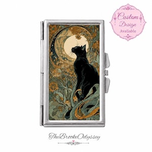 Pode incluir: Um estojo retangular de metal prateado com uma impressão artística de um gato preto sentado entre folhagens e flores em tons dourados sob uma lua grande e pálida. O estojo tem uma lateral articulada e uma moldura metálica. Um emblema rosa diz Custom Design Avaliable.