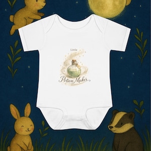 May include: White baby onesie with a whimsical illustration of a potion bottle, the text "Little Potion Maker", and a night scene with bunnies, a badger, a moon, and stars. The design is set against a dark blue background.