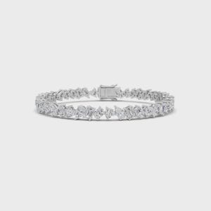 Könnte beinhalten: Ein silbernes Armband mit einer Vielzahl klarer, funkelnder Edelsteine in verschiedenen Formen, darunter runde, smaragd- und tropfenförmige Schliffe. Das Armband hat einen sicheren Verschluss und ist für das Handgelenk konzipiert. Die Edelsteine sind eng gesetzt und bilden ein durchgehendes Band.