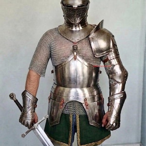 Könnte beinhalten: Eine vollständige mittelalterliche Rüstung, einschließlich Helm, Brustplatte, Schulterschutz, Arm- und Handschutz sowie ein Hüftschutz. Die Rüstung ist silberfarben und wird über einem Kettenhemd getragen. Ein Schwert wird in der rechten Hand gehalten. Grüne und goldene Verzierungen sind sichtbar.