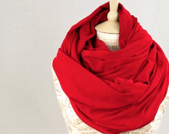 May include: A red infinity scarf made of soft fabric. The scarf is draped over a mannequin with a vintage pattern.