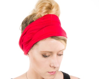Könnte beinhalten: Eine Frau mit blonden Haaren trägt ein rotes Stirnband und ein schwarzes Tanktop. Sie trägt eine silberne Halskette mit einem Anhänger. Sie hat ein Blumen-Tattoo auf ihrem rechten Arm.