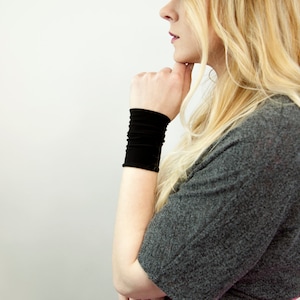 May include: A woman wearing a gray shirt and a pink skirt with a black wrist cuff.