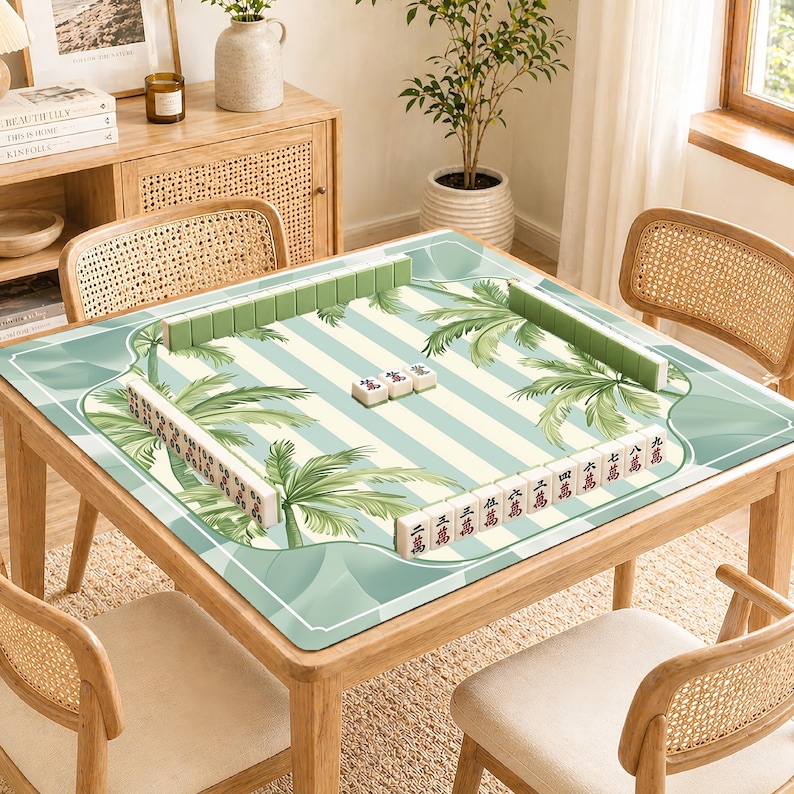 Pode incluir: Uma mesa de madeira com um tapete de Mahjong listrado em verde e branco com desenhos de palmeiras. A mesa est&aacute; montada com pe&ccedil;as de Mahjong verdes e brancas, prontas para jogar. A mesa &eacute; rodeada por cadeiras de vime.